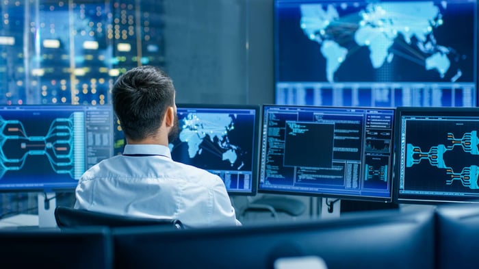 Operator at a control room desk monitoring network data on several screens